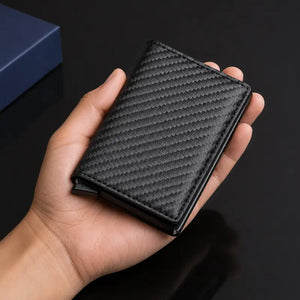 Carteira masculina slim Bastião Carbon preta fechada na mão mostrando o tamanho compacto